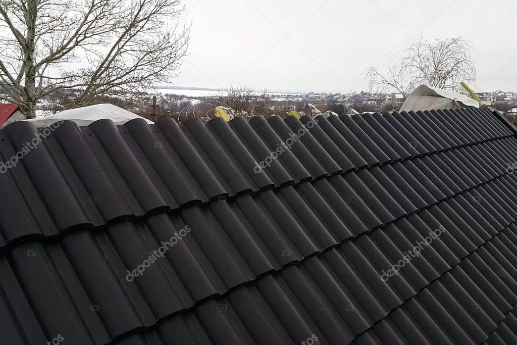 Installation of the roof of the house from ceramic black tiles.