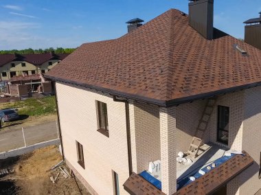 Yeni tuğla ev. Çatı için küçük fayanslar. Çatısı olan ev.