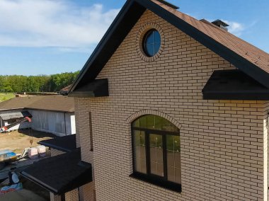 Yeni tuğla ev. Çatı için küçük fayanslar. Çatısı olan ev.