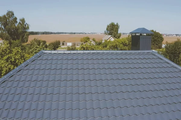 Gray-blue metal roof tiles on the roof of the house. Corrugated