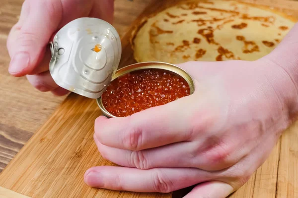 Opening jar of red salmon caviar.