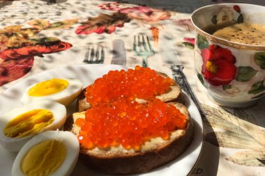 Kırmızı havyarlı sandviç, haşlanmış yumurta, kahve fincanı. Günaydın.