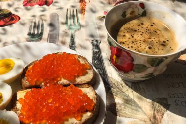 Kırmızı havyarlı sandviç, haşlanmış yumurta, kahve fincanı. Günaydın.