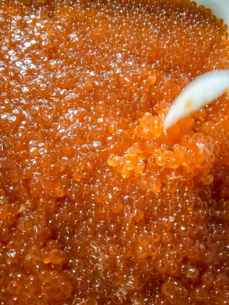 Caviar rojo en un recipiente de plástico. Agitación con una cuchara de plástico o —  Fotos de Stock