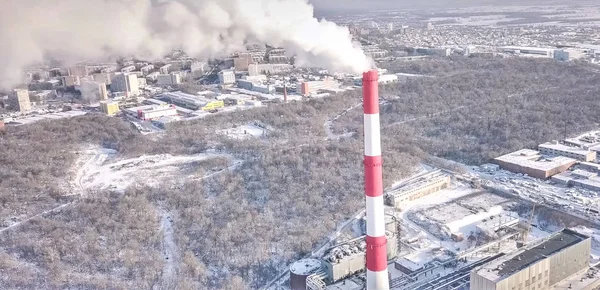 Rökning skorsten i ett värmekraftverk på bakgrunden av vintern stad. — Stockfoto