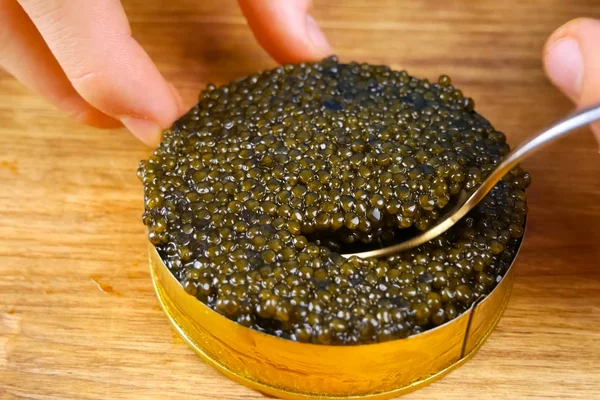 Black caviar in cardboard box. Spooning black caviar. — Stock Image Black caviar in cardboard box. Spooning black caviar. Stock Picture