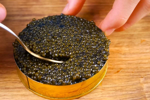 Black caviar in cardboard box. Spooning black caviar. — Stock Image Black caviar in cardboard box. Spooning black caviar. Stock Image