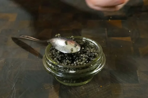 Agitar el caviar negro con una cuchara en un frasco de vidrio . — Foto de Stock