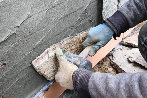 Builder faces the basement of a house with a wild stone. Flat fo — Stock Photo, Image