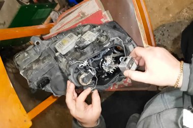 Ksenon lambası bir elektrikçinin elinde. Ksenon lambaları değiştiriliyor.