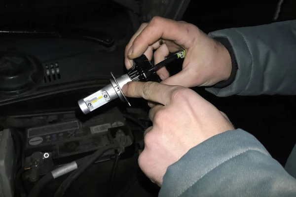 Xenon lamp in hands of an electrician. Replacing xenon lamps. — Stock Photo, Image