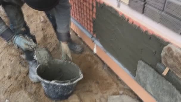 一个建筑商面对着一幢房子的地下室 用一块野生的石头 建筑工地填充物 塔瓦塔的平面 — 图库视频影像