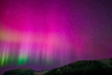 Kuzey gökyüzünde Aurora Borealis. Üst atmosferde hava parçacıklarının iyonlaşması.
