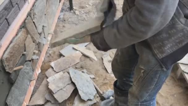 Costruttore si affaccia sul seminterrato di una casa con una pietra selvaggia. Piatto per rivestimento, tabata sul cantiere . — Video Stock
