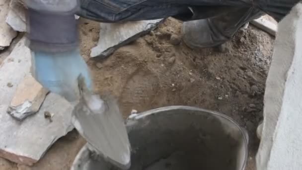 Der Bauarbeiter steht vor dem Keller eines Hauses mit einem wilden Stein. Wohnung für Verkleidungen, Tabata auf der Baustelle. — Stockvideo