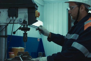 Sondaj makinesinin arkasında çalışan bir işçi. Fabrikada kilit olarak çalış.