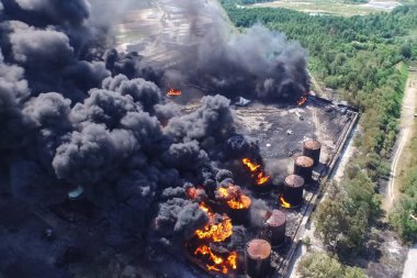 Oil storage fire. The tank farm is burning, black smoke is combu clipart