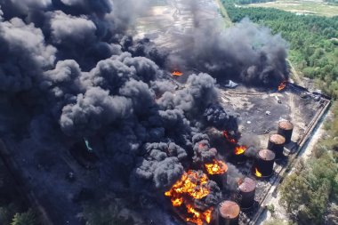 Oil storage fire. The tank farm is burning, black smoke is combu clipart