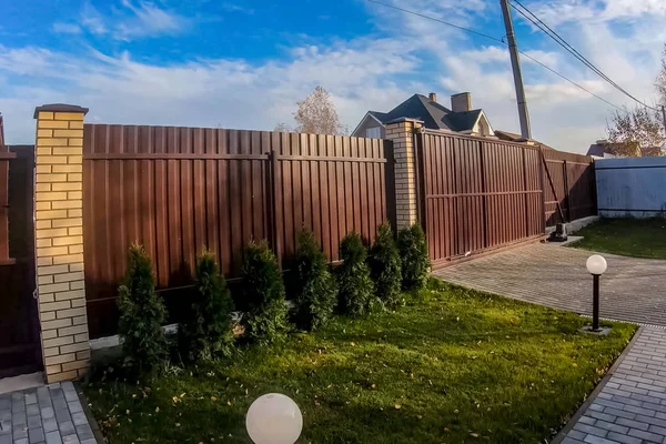 Çit ve kapı kahverengi kıvrımlı metal profilden yapılmış.