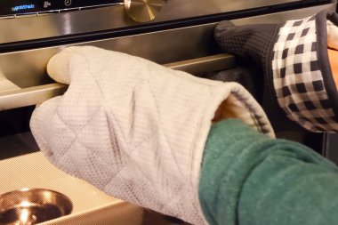 Sıcak için eldiven. Aşçı fırını açar..