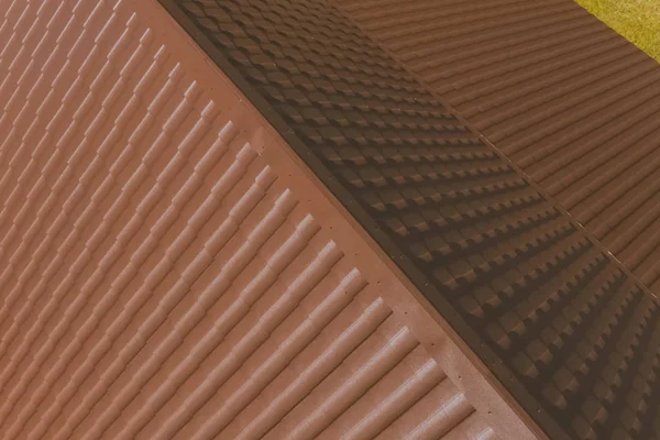 Brown metal tile on the roof of the house. Corrugated metal roof