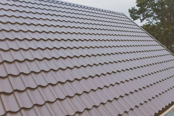 Mattonelle di metallo marrone sul tetto della casa. tetto in metallo ondulato — Foto Stock