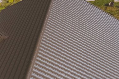 Evin çatısında kahverengi metal fayans var. Oluklu metal çatı