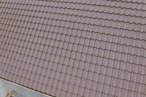 Brown metal tile on the roof of the house. Corrugated metal roof