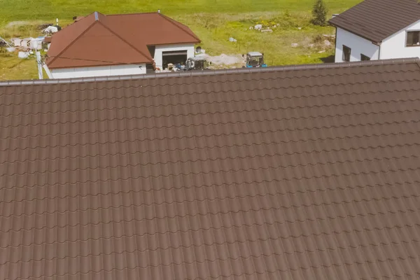 Brown metal tile on the roof of the house. Corrugated metal roof