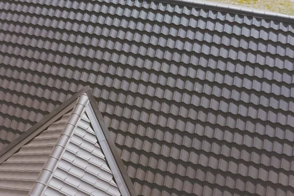 Brown metal tile on the roof of the house. Corrugated metal roof