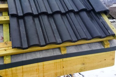 Evin çatısının seramik siyah fayanslardan kurulumu.