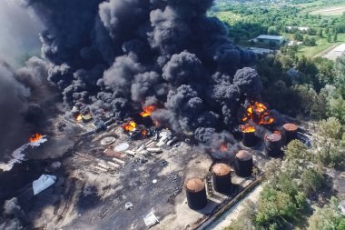Oil storage fire. The tank farm is burning, black smoke is combu clipart