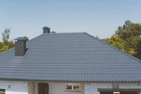 Gray-blue metal roof tiles on the roof of the house. Corrugated