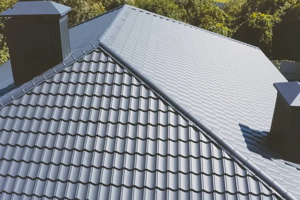 Gray-blue metal roof tiles on the roof of the house. Corrugated