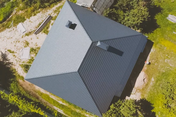 Gray-blue metal roof tiles on the roof of the house. Corrugated