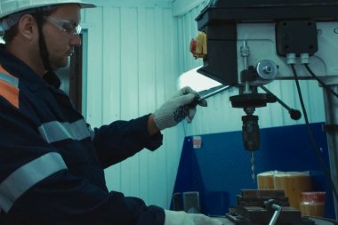 Sondaj makinesinin arkasında çalışan bir işçi. Fabrikada kilit olarak çalış.