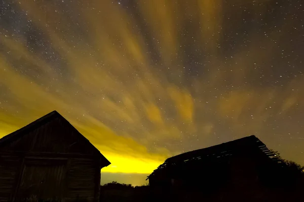 Cielo estrellado sobre casas de madera en el pueblo. Imagen de fondo del cielo estrellado de estrellas en el cielo nocturno y la Vía Láctea . — Foto de Stock