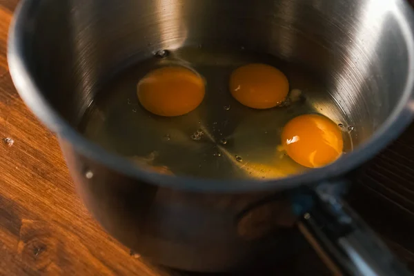 Σπάσιμο αυγών σε κατσαρόλα, ωμά αυγά για ξυλοδαρμό. — Φωτογραφία Αρχείου