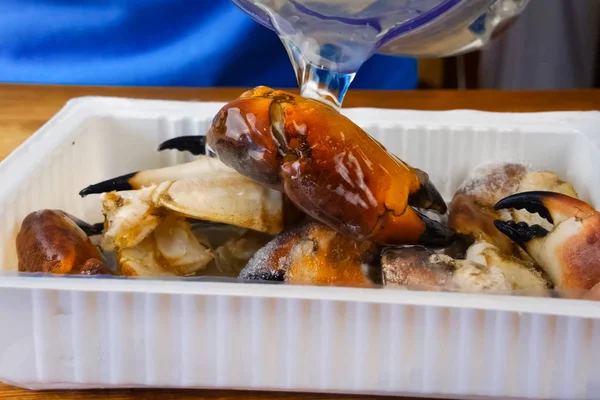 Gli artigli di granchio sono versati con salsa. Frutti di mare in contenitore di plastica . — Foto Stock