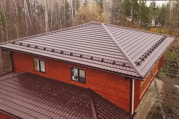 Casa com um telhado de metal marrom. Telhado de metal ondulado e metal ro — Fotografia de Stock