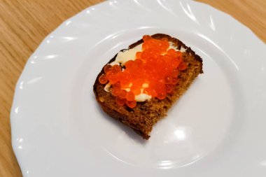 Tereyağlı sandviç ve tabakta kırmızı havyar.