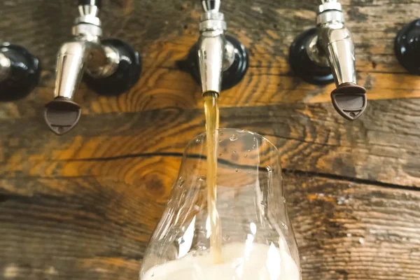 Bier in een glas gieten uit de kraan aan de bar. Bierbotteling. — Stockfoto