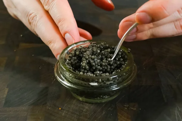 Agitando caviar preto com uma colher em frasco de vidro . — Fotografia de Stock