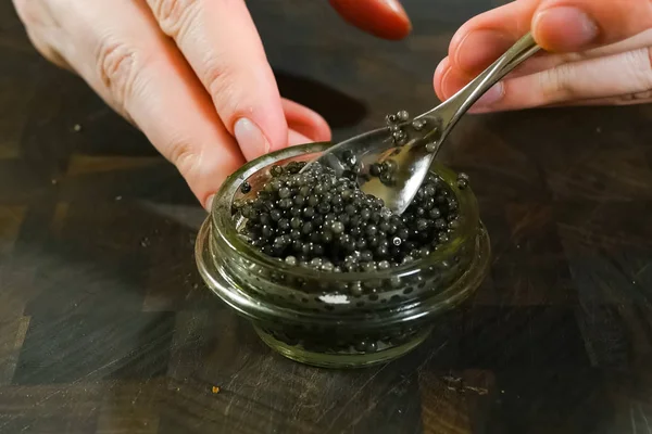 유리병에 숟가락을 넣고 검은 캐비어를 저으는 모습. — 스톡 사진