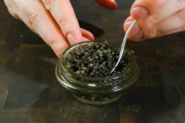 Caviale nero mescolante con un cucchiaio in vaso di vetro . — Foto Stock