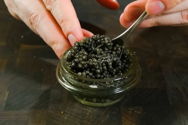 Ανακατεύοντας μαύρο χαβιάρι με κουτάλι σε γυάλινο βάζο. — Φωτογραφία Αρχείου