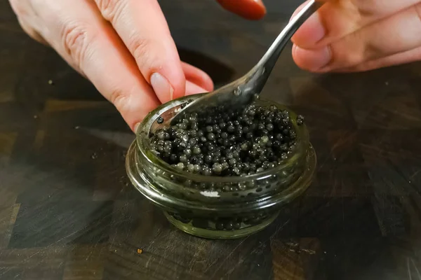 Agitando caviar preto com uma colher em frasco de vidro . — Fotografia de Stock