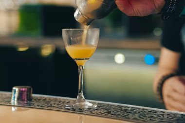Barmen tezgahta kokteyl dolduruyor.