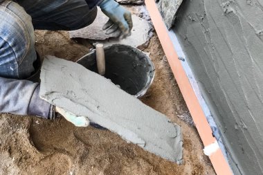 İnşaatçı elinde vahşi bir taş olan bir evin bodrumuna bakıyor. Düz fo