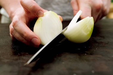 Mutfakta kesme tahtasında soğan kesme.